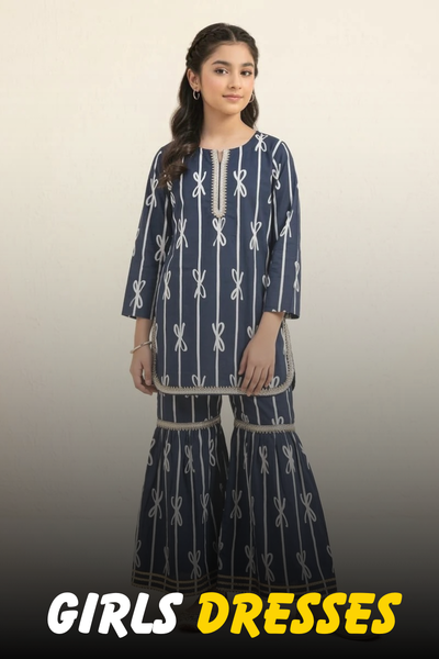 A young girl wearing a navy blue printed kurti with a matching gharara set featuring white bow patterns and lace trim from Nazz Collections.